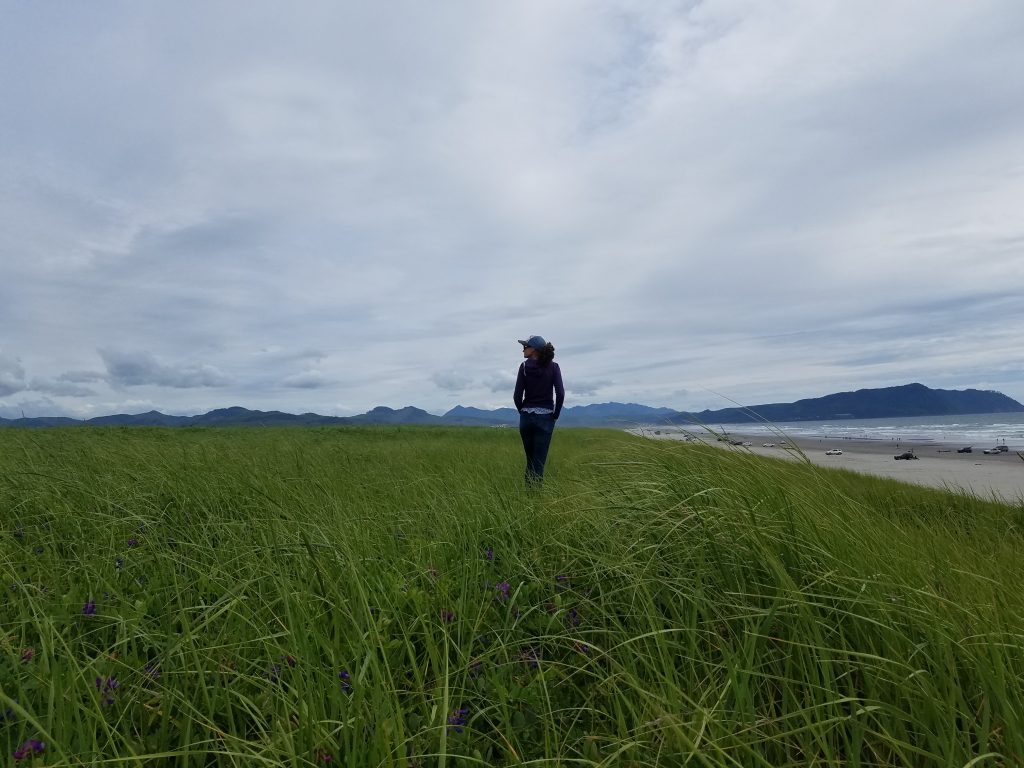 United States Simple Guide Insider Tips. This photo is of my sister on the Oregon coast. Mountain range in the distance.